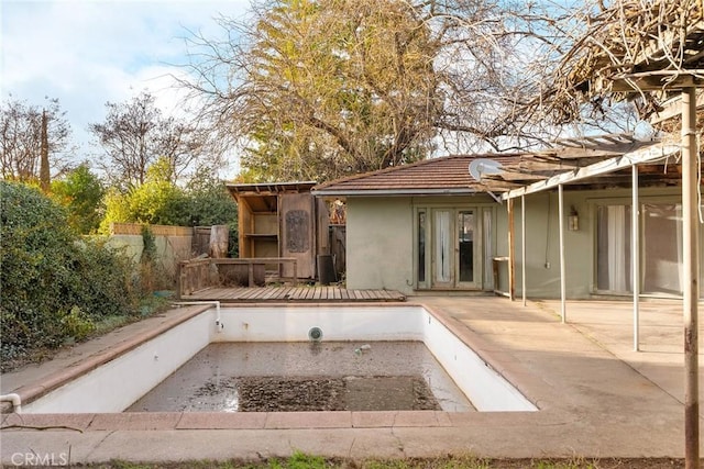 rear view of house with a deck, fence, a tiled roof, stucco siding, and a patio area