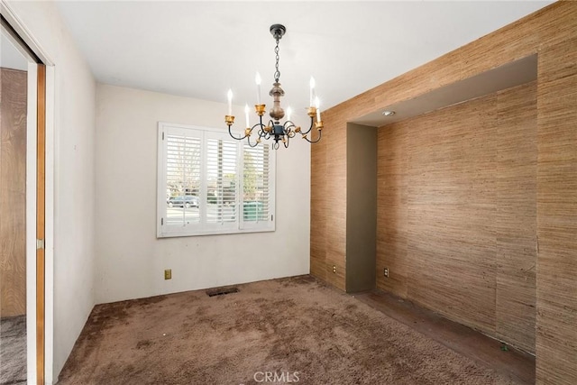 unfurnished dining area with carpet floors, visible vents, and a notable chandelier