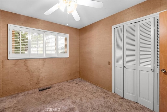 unfurnished bedroom with a closet, carpet, visible vents, and a ceiling fan