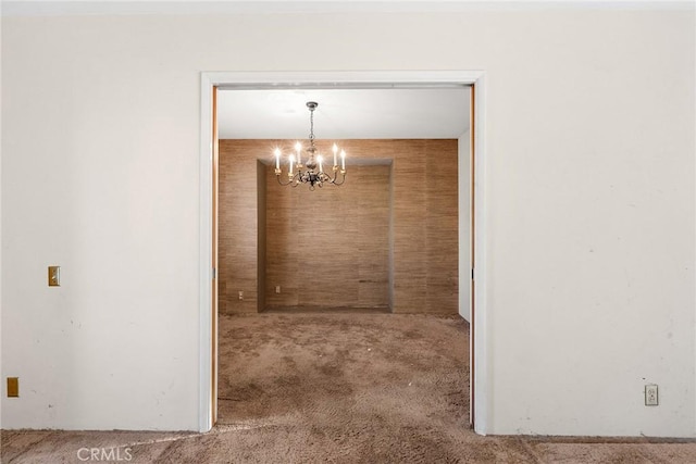 unfurnished dining area featuring carpet floors and an inviting chandelier