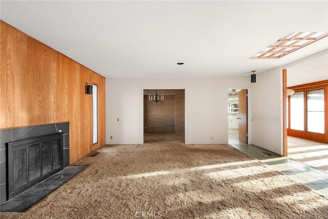 unfurnished living room featuring a fireplace with flush hearth, carpet flooring, and wooden walls