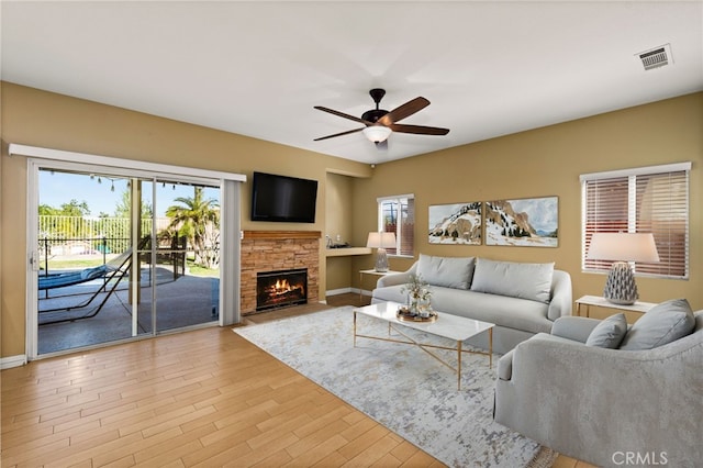 living room featuring a healthy amount of sunlight, a fireplace, visible vents, and wood finished floors