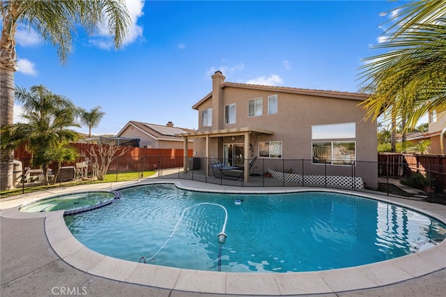 view of pool featuring a patio, a fenced backyard, and a pool with connected hot tub