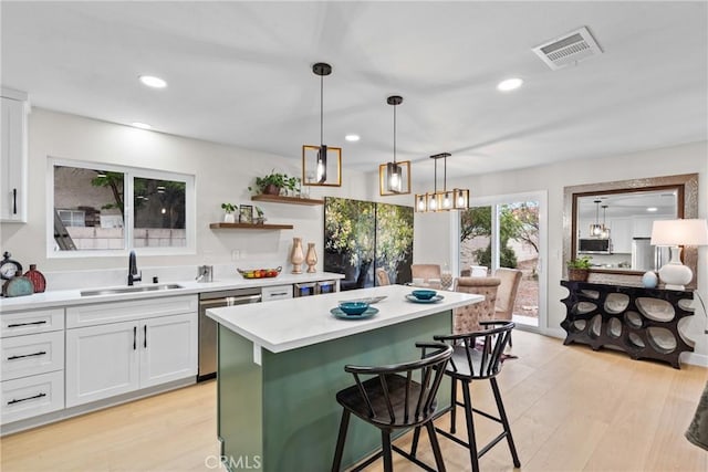 kitchen featuring visible vents, a sink, stainless steel appliances, light countertops, and white cabinetry