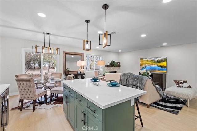 kitchen with open floor plan, light wood-style flooring, a kitchen island, and green cabinetry