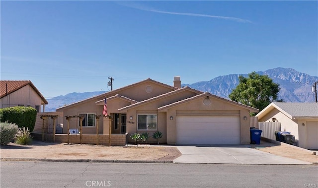 single story home featuring driveway, a garage, fence, a mountain view, and stucco siding