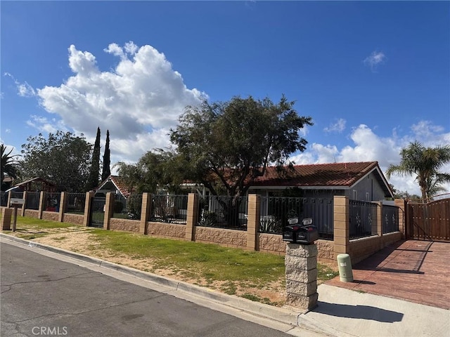 view of front of house featuring a fenced front yard, a tile roof, and a gate