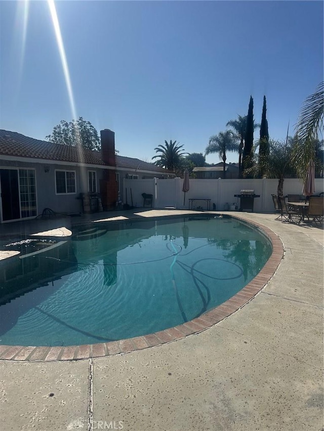 view of swimming pool featuring fence, grilling area, a fenced in pool, and a patio