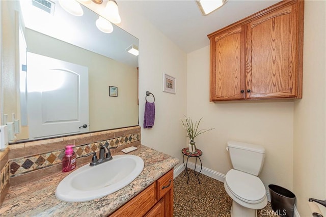 half bath featuring toilet, visible vents, baseboards, and vanity