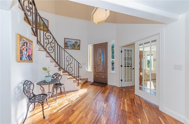 entrance foyer with stairs, vaulted ceiling, wood finished floors, and baseboards