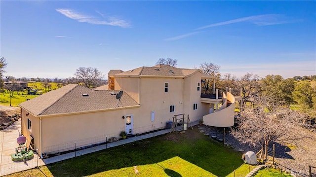 view of side of home featuring roof with shingles, a yard, and stucco siding