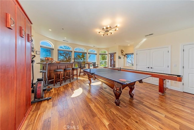 recreation room with a bar, light wood-style floors, and visible vents