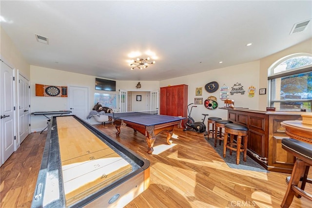 recreation room with a dry bar, light wood-type flooring, and visible vents