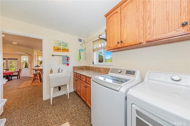 laundry area featuring arched walkways, visible vents, baseboards, cabinet space, and washer and clothes dryer