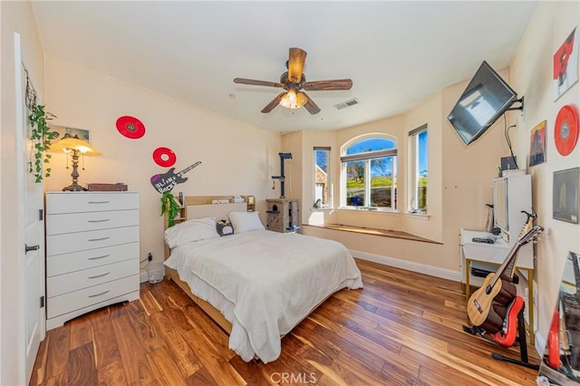 bedroom featuring a ceiling fan, baseboards, visible vents, and wood finished floors