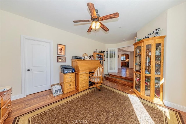 office with light wood-style floors, arched walkways, ceiling fan, and baseboards