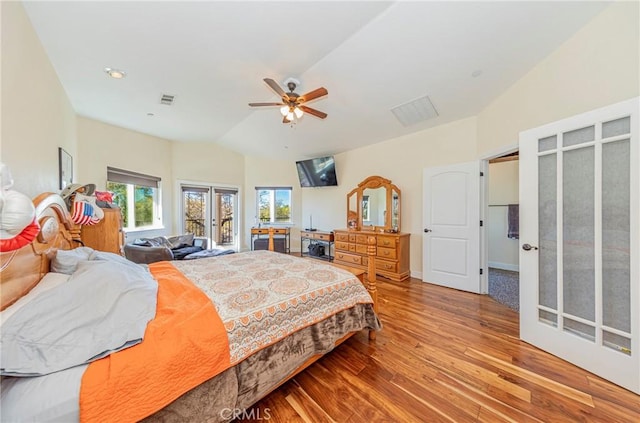 bedroom featuring visible vents, a ceiling fan, wood finished floors, access to outside, and vaulted ceiling