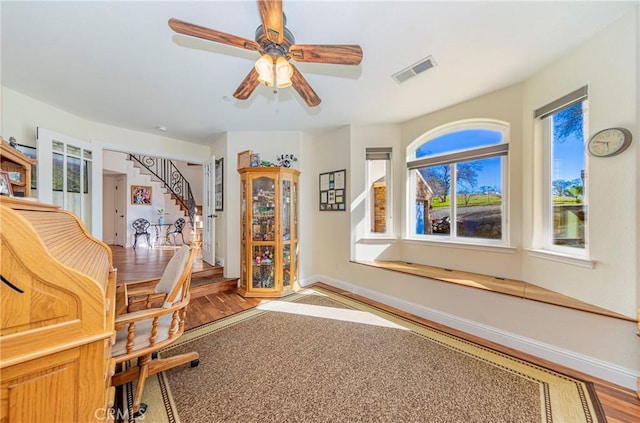 office area featuring a ceiling fan, visible vents, baseboards, and wood finished floors