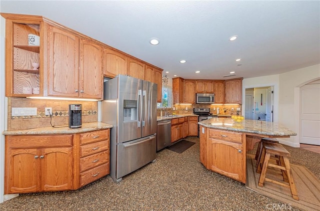 kitchen with arched walkways, a center island, stainless steel appliances, recessed lighting, and decorative backsplash