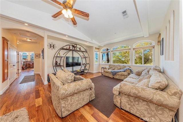 living room with arched walkways, wood finished floors, visible vents, baseboards, and vaulted ceiling