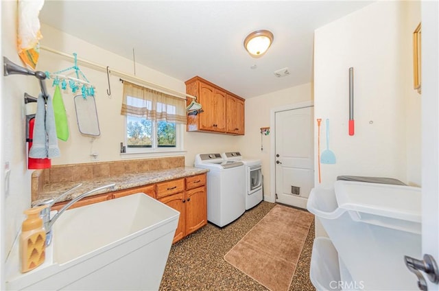 washroom featuring a sink, washing machine and dryer, and cabinet space