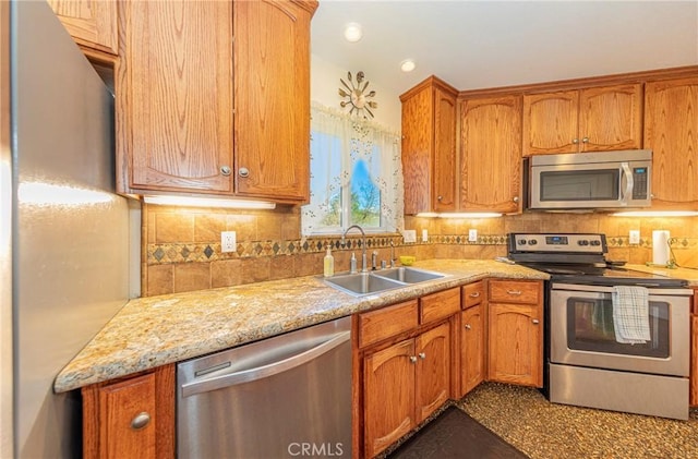 kitchen with appliances with stainless steel finishes, brown cabinetry, a sink, and tasteful backsplash