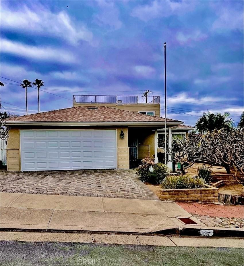 view of front of property featuring driveway, an attached garage, and a balcony