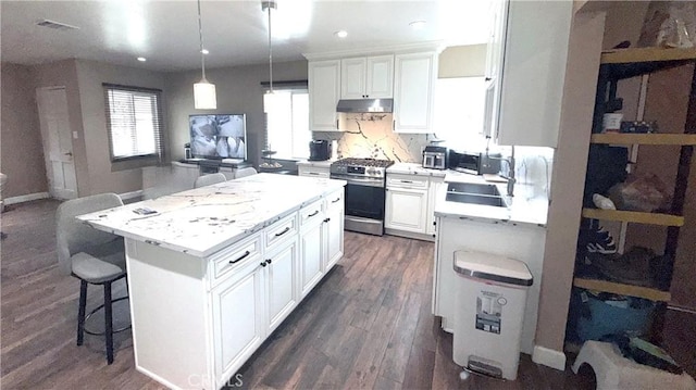 kitchen with light countertops, white cabinets, stainless steel gas stove, and under cabinet range hood