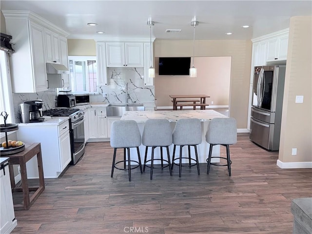 kitchen featuring stainless steel appliances, a kitchen island, a sink, and white cabinetry