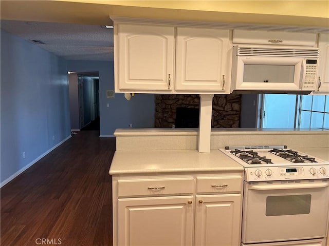 kitchen with white appliances, visible vents, baseboards, white cabinets, and dark wood-style floors