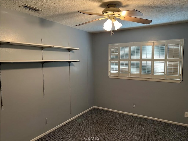 empty room featuring baseboards, visible vents, ceiling fan, dark colored carpet, and a textured ceiling