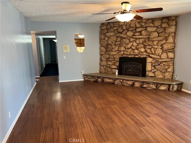 unfurnished living room with baseboards, ceiling fan, wood finished floors, a textured ceiling, and a fireplace