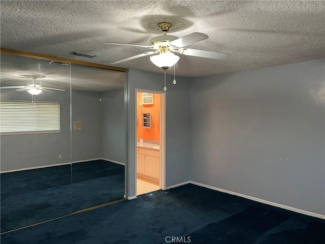 empty room with ceiling fan, a textured ceiling, visible vents, and baseboards