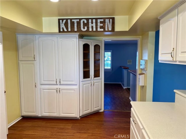 kitchen with dark wood-style floors, light countertops, baseboards, and white cabinets