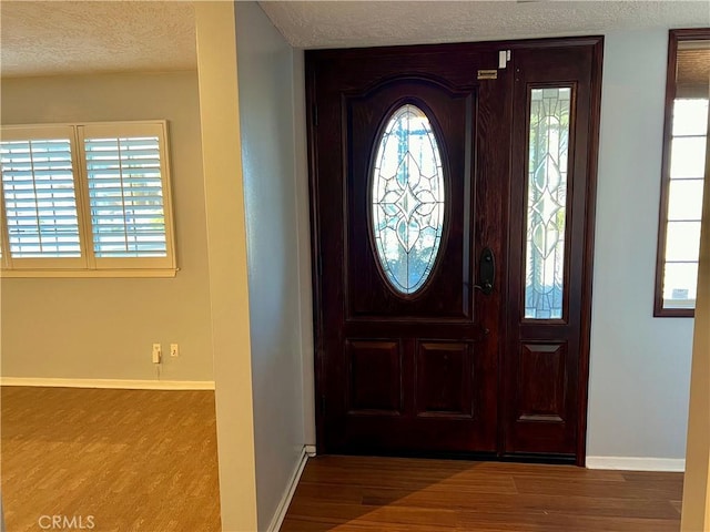 foyer featuring a textured ceiling, baseboards, and wood finished floors