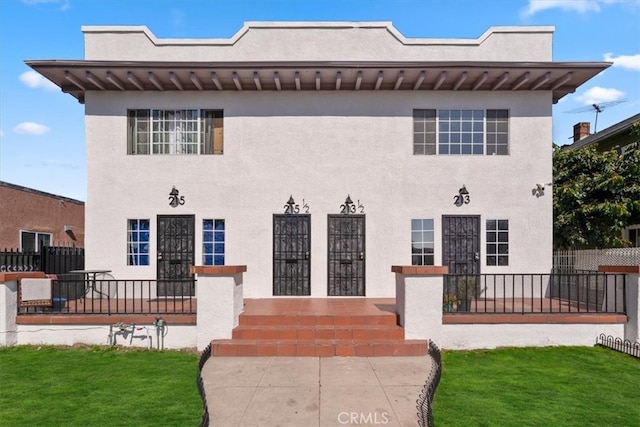 view of front facade with fence and stucco siding