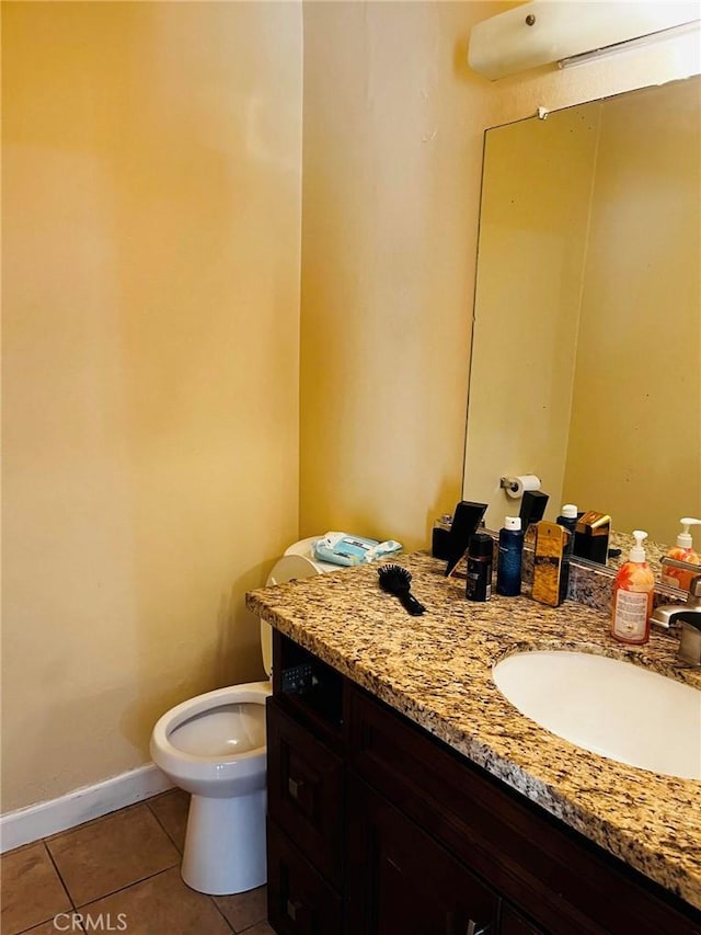 half bathroom featuring toilet, tile patterned flooring, baseboards, and vanity