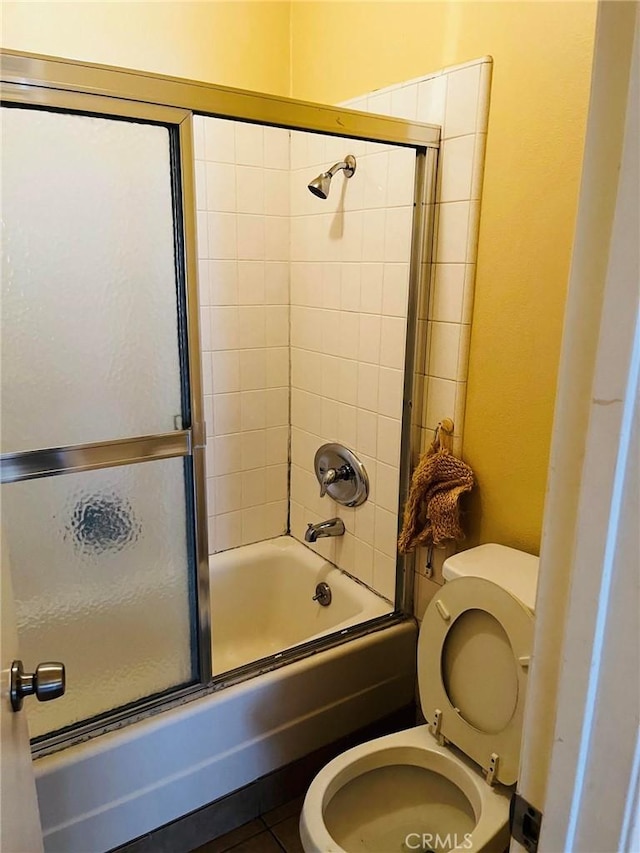 full bath with shower / bath combination with glass door, toilet, and tile patterned floors