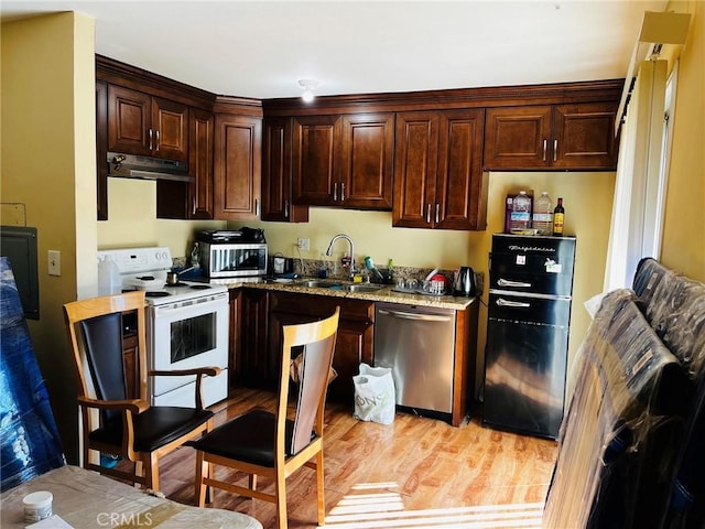 kitchen with appliances with stainless steel finishes, a sink, under cabinet range hood, and dark brown cabinets