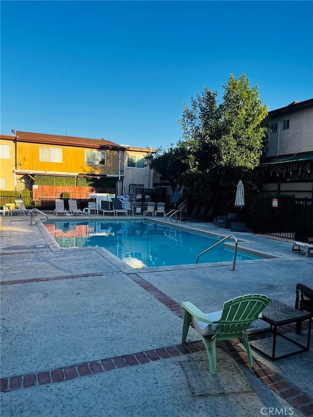 community pool with a patio and fence