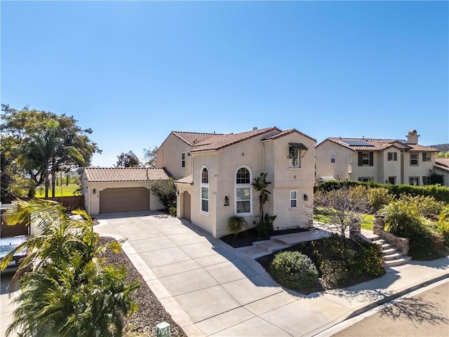 mediterranean / spanish home with concrete driveway, a tile roof, an attached garage, and stucco siding