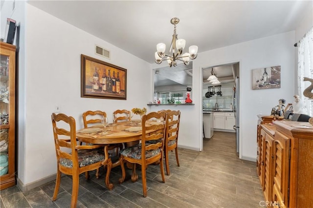 dining room featuring a chandelier, wood finished floors, visible vents, and baseboards