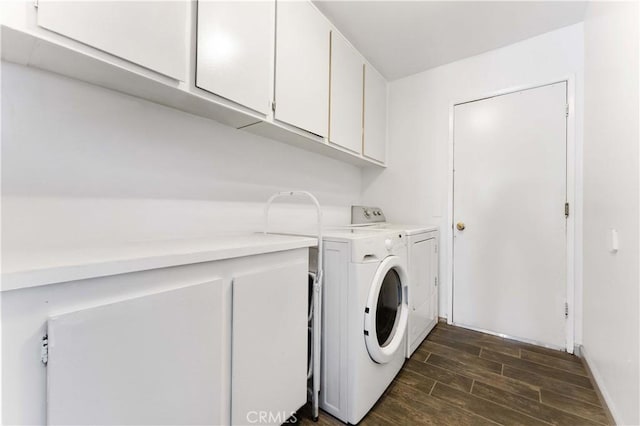 clothes washing area featuring wood tiled floor, cabinet space, and washing machine and clothes dryer