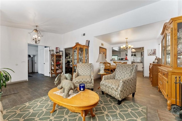 living area featuring an inviting chandelier, baseboards, visible vents, and wood finished floors