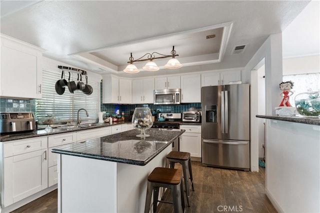 kitchen featuring appliances with stainless steel finishes, a raised ceiling, visible vents, and white cabinets