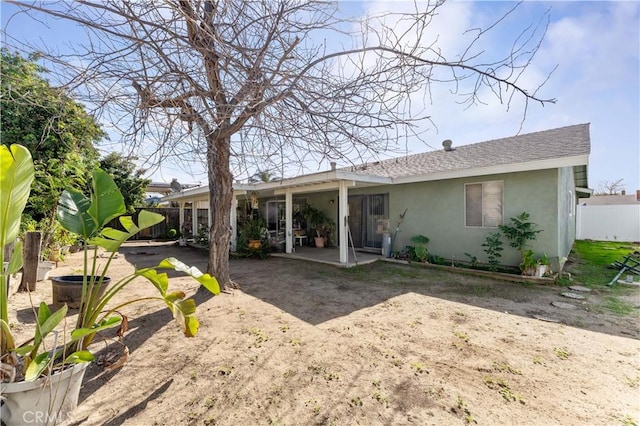 back of property with a shingled roof, a patio area, fence, and stucco siding