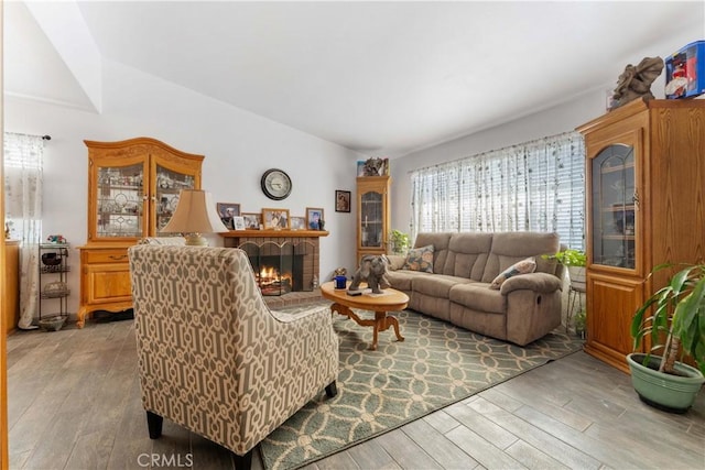 living room with light wood-style floors, lofted ceiling, and a fireplace