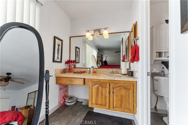 bathroom featuring ceiling fan, toilet, wood finish floors, vanity, and baseboards