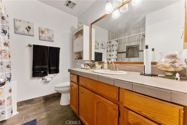 full bath with curtained shower, toilet, wood finished floors, vanity, and visible vents