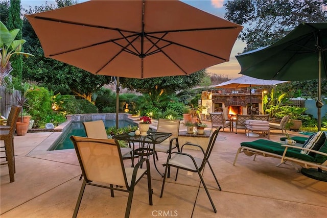 view of patio / terrace featuring fence, an outdoor stone fireplace, and an outdoor pool